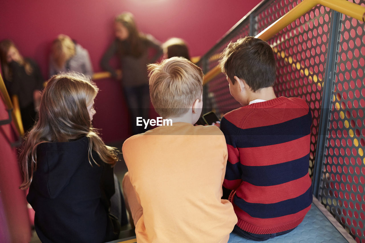 Rear view of junior high students sitting on staircase