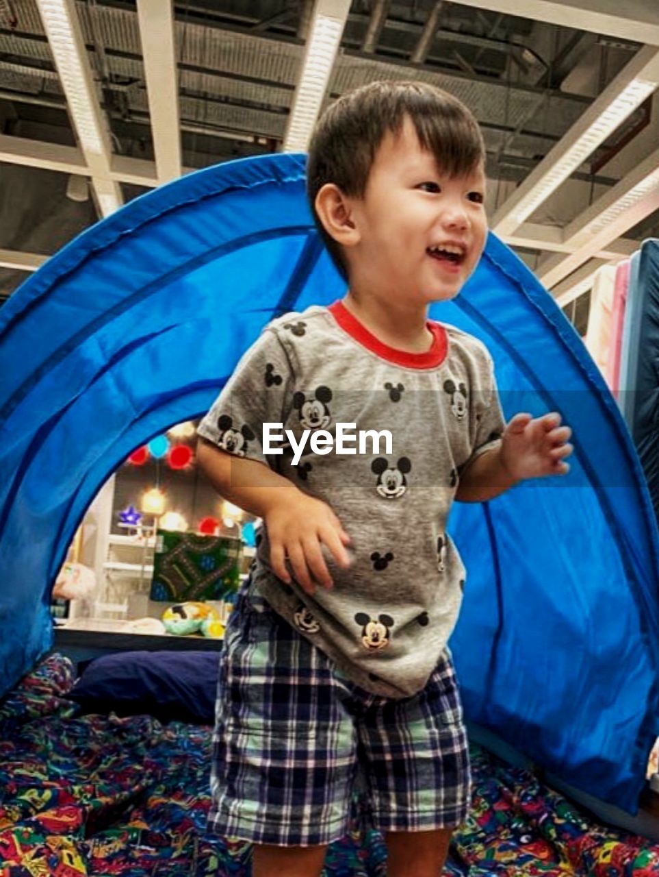 BOY STANDING ON BED IN BEDROOM