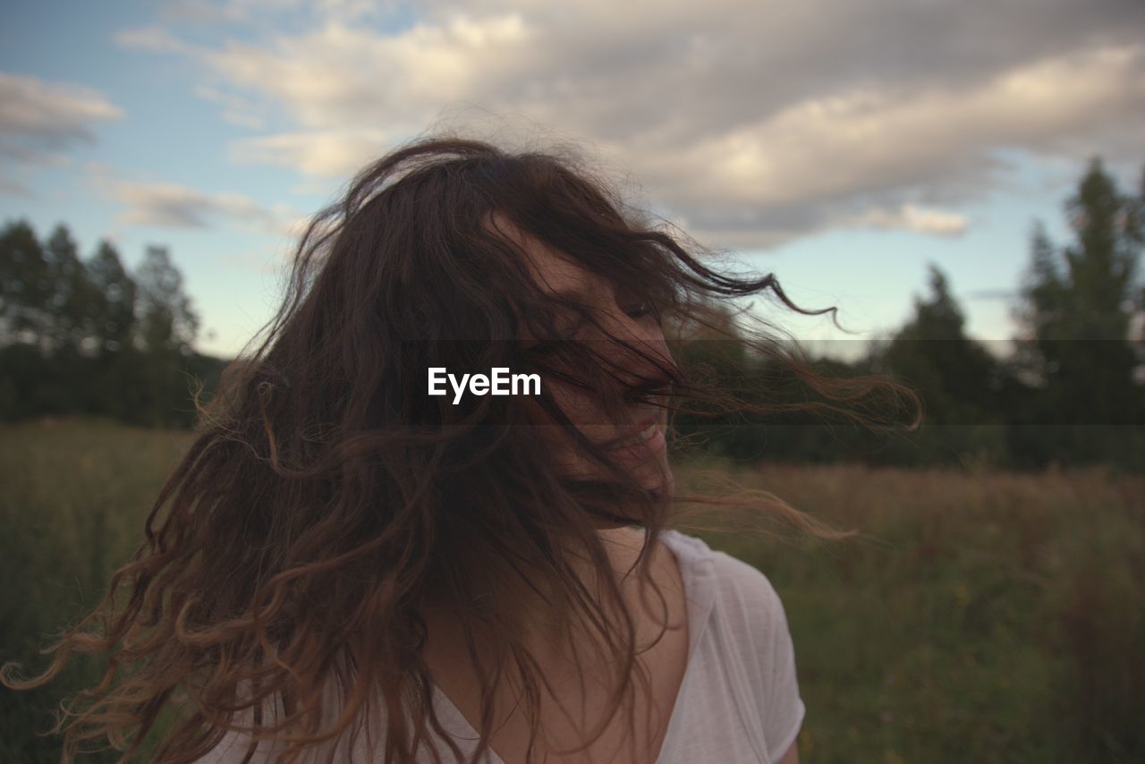 Cheerful woman tossing hair on field