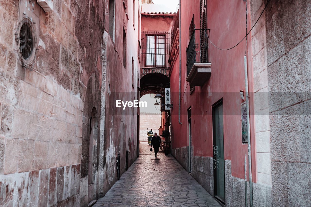 People walking in alley amidst buildings