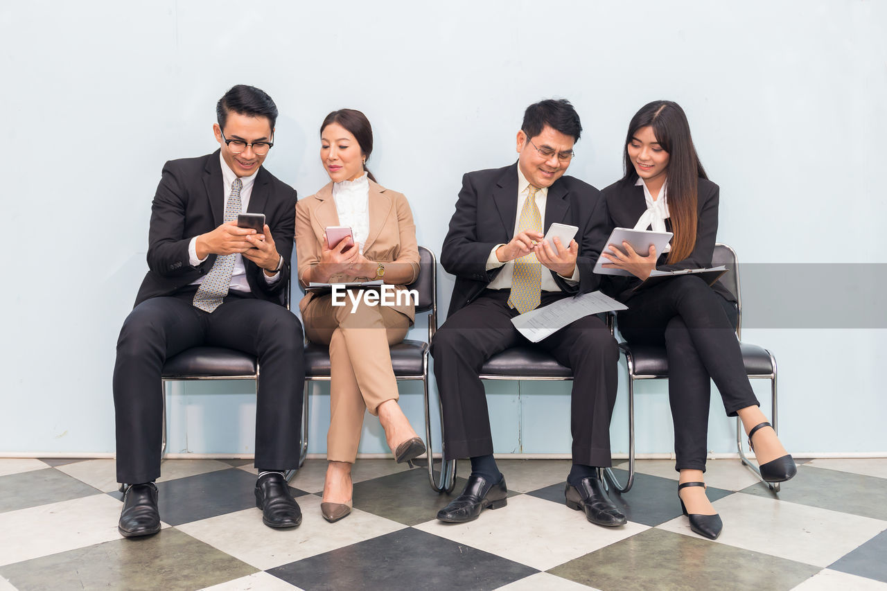 Business people using technologies while sitting on chairs at office