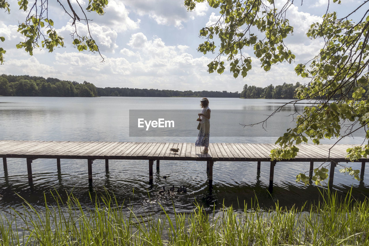 Woman standing  by lake against sky