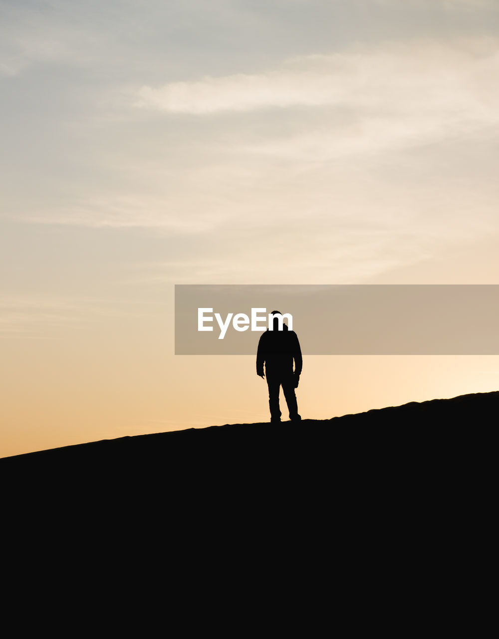 Silhouette of woman standing on landscape at sunset