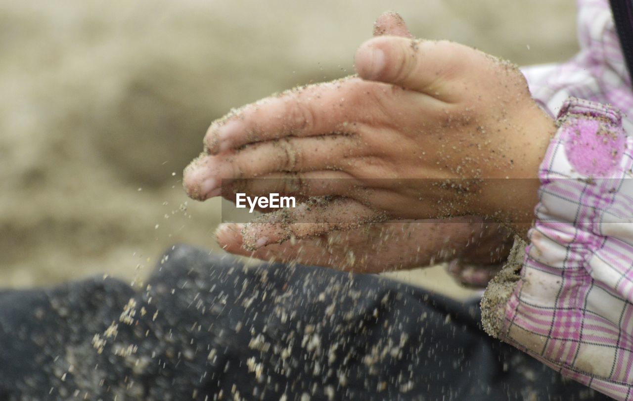 Cropped hands of child spilling sand
