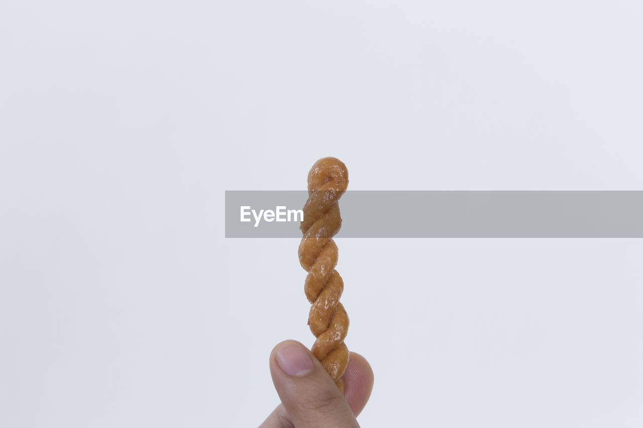 Close-up of hand holding bread against white background