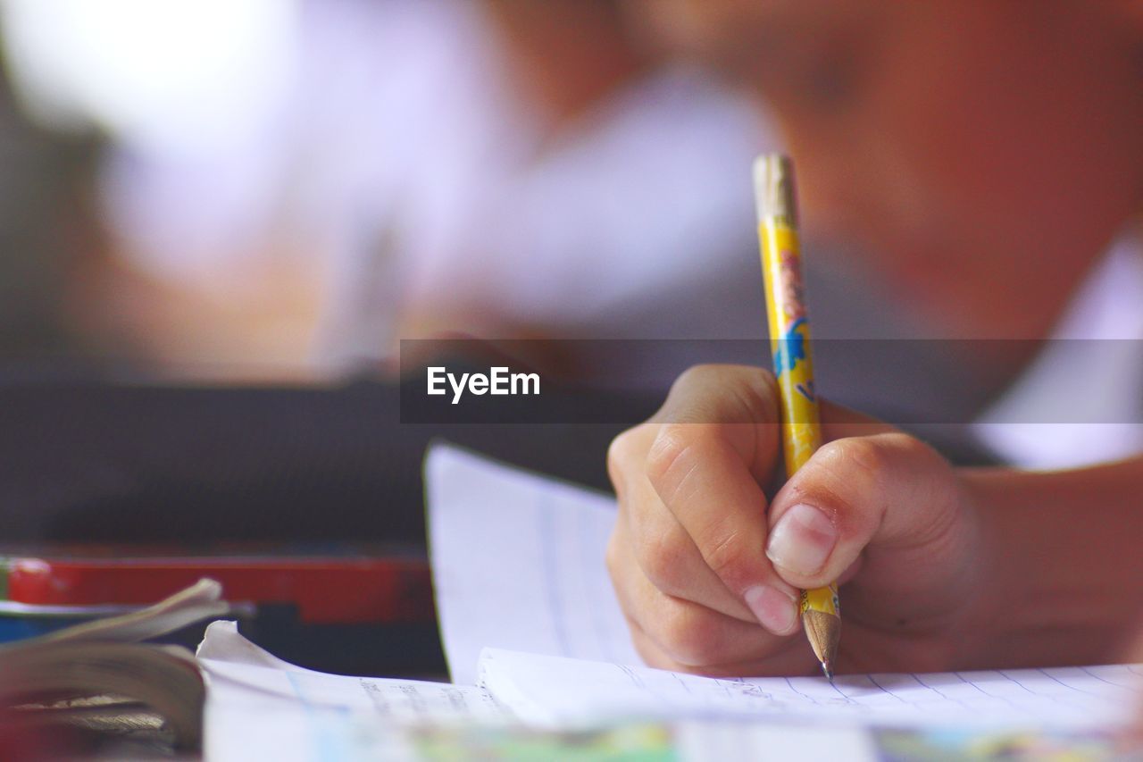 Cropped of hand of child writing on book on desk