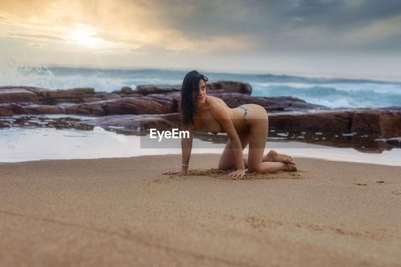 FULL LENGTH OF WOMAN ON BEACH AGAINST SKY