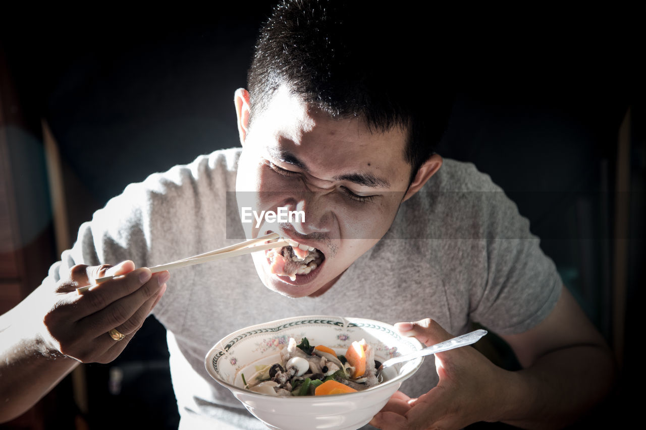PORTRAIT OF YOUNG MAN EATING FOOD