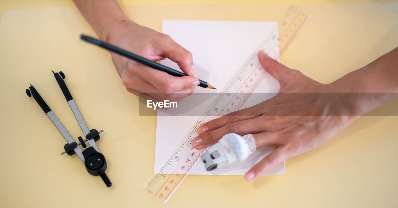 cropped hands of woman writing in book