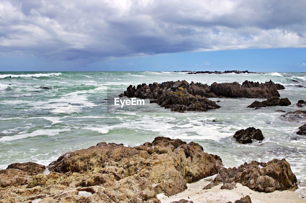 Scenic view of rocks on beach against sky