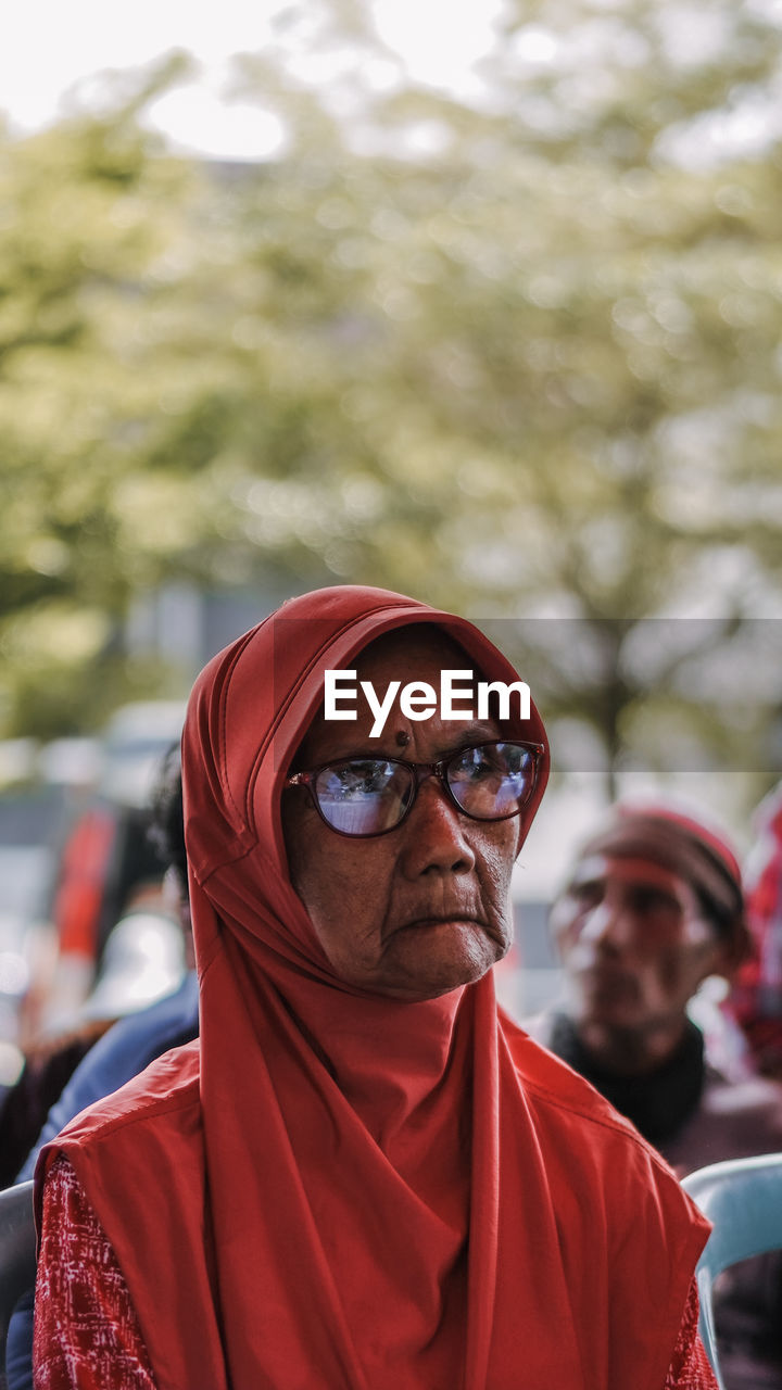 Woman with eyeglasses standing against trees