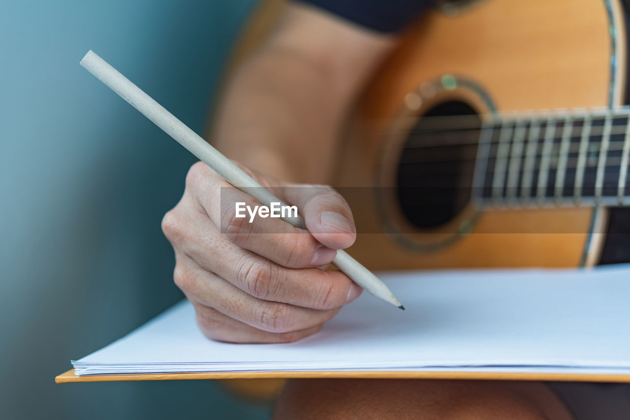 cropped hand of man writing in book at table