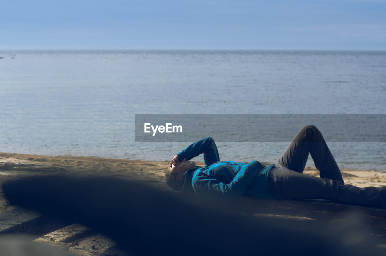 Woman resting on the beach in outdoor clothes. select focus