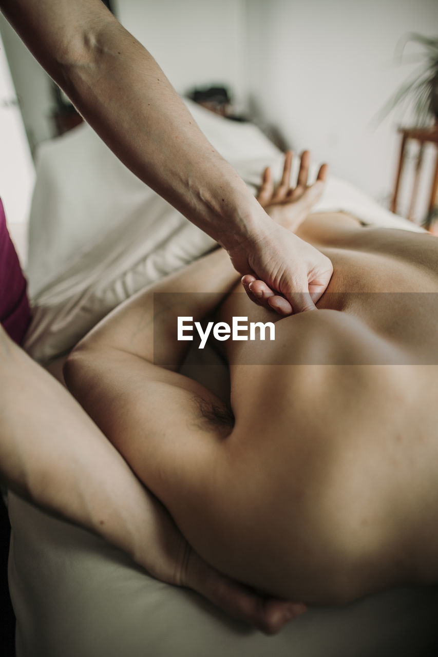 Massage therapist works on shoulder of a her male patient