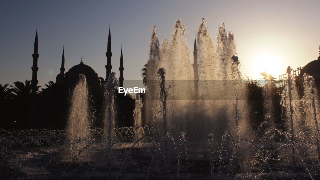 Fountain at silhouette sultan ahmed mosque against clear sky during sunset