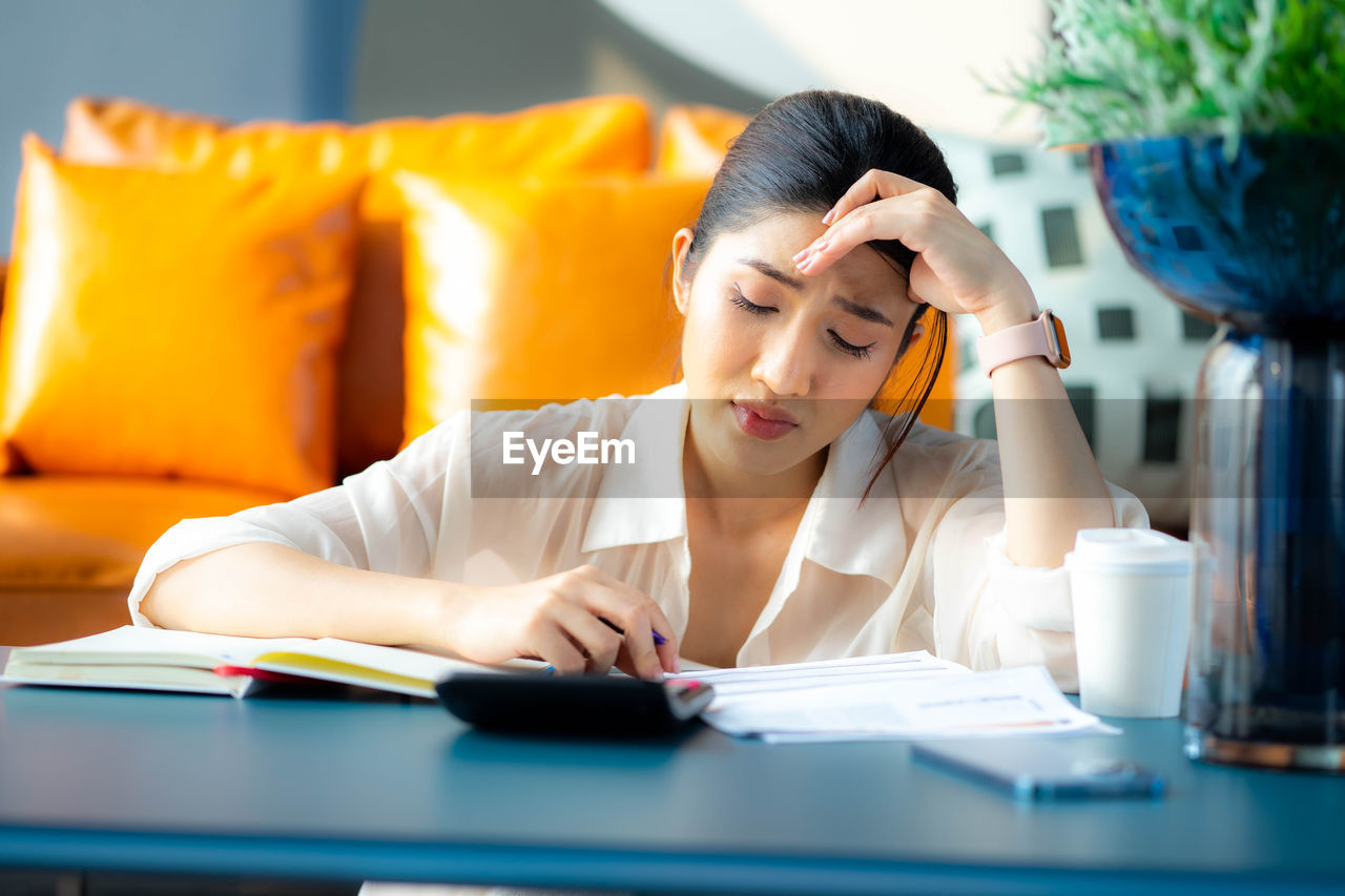 young woman using mobile phone while sitting at table