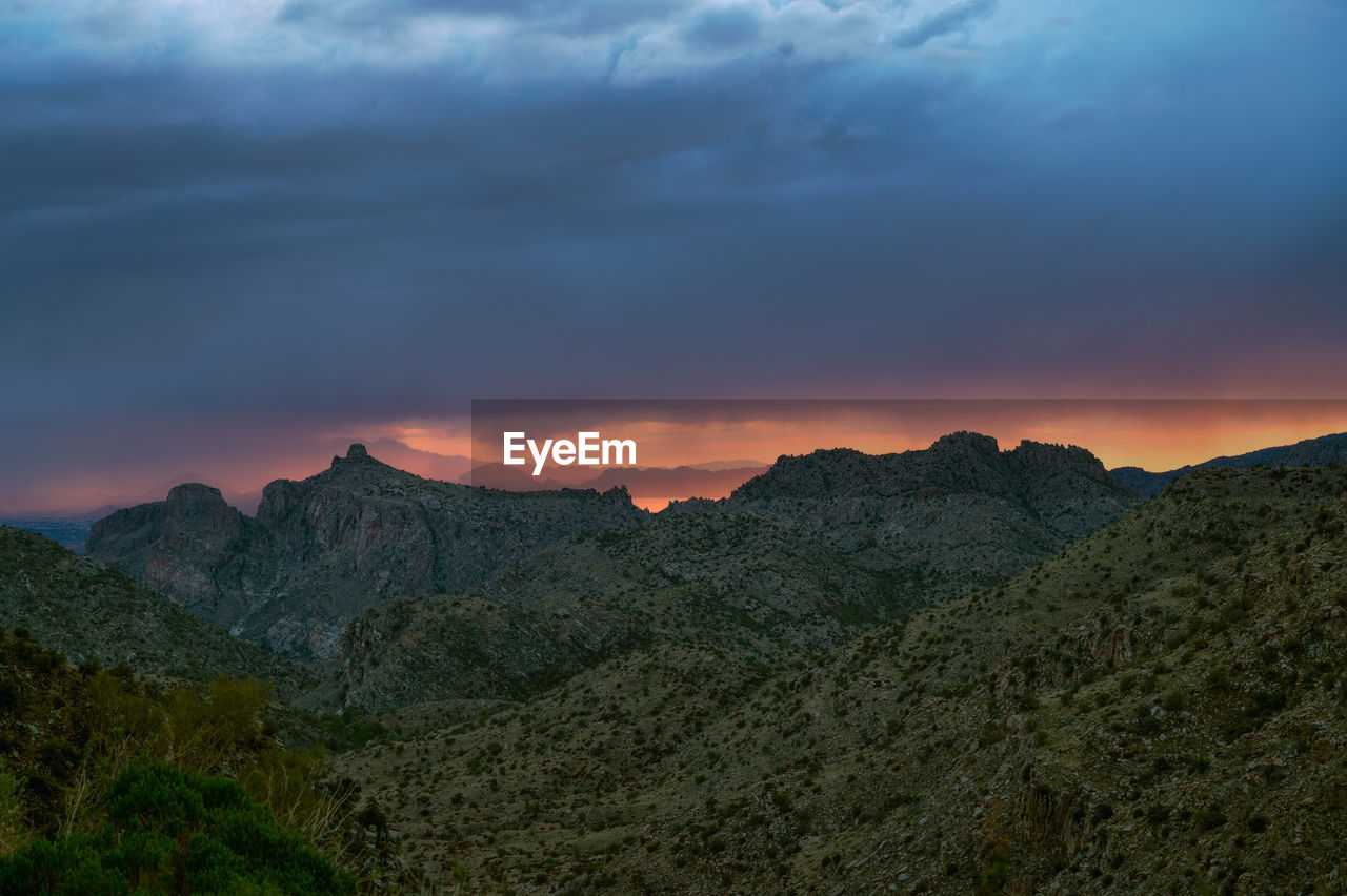 Dramatic sunset sky with monsoon rain over thimble peak in tucson, arizona.