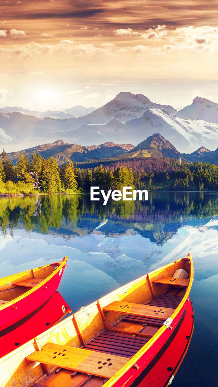 BOATS MOORED ON LAKE AGAINST SKY