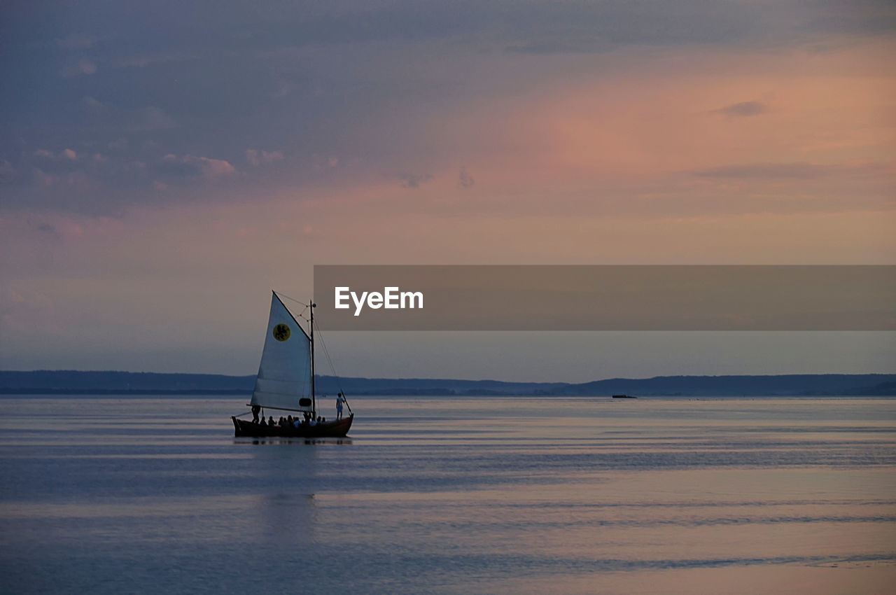 Sailboat sailing on sea against sky during sunset