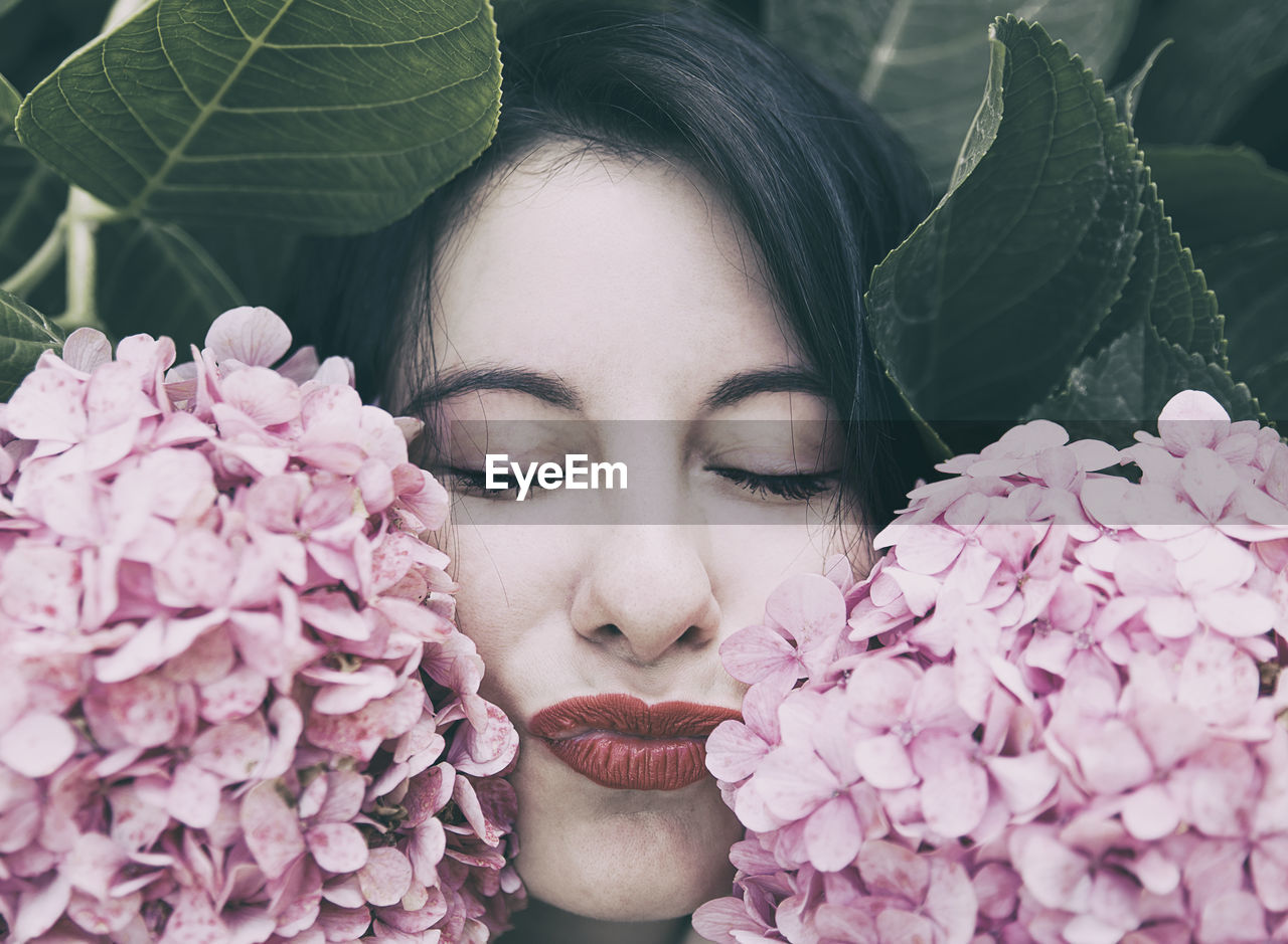 Close-up of woman with eyes closed by pink flowers