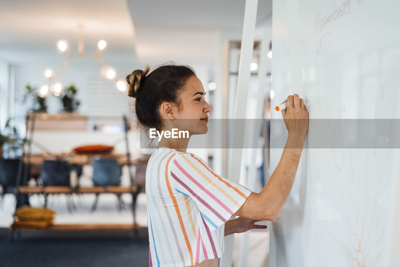 Businesswoman writing on whiteboard in office