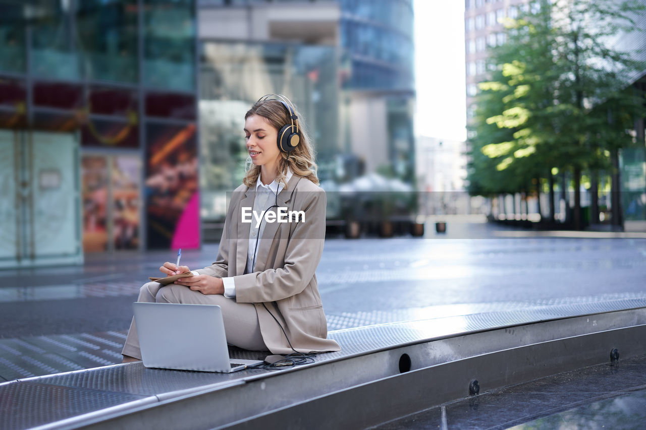 portrait of young woman using mobile phone in city