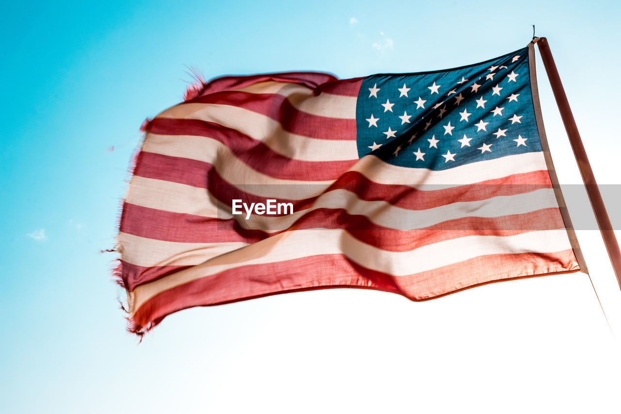 Low angle view of american flag against blue sky