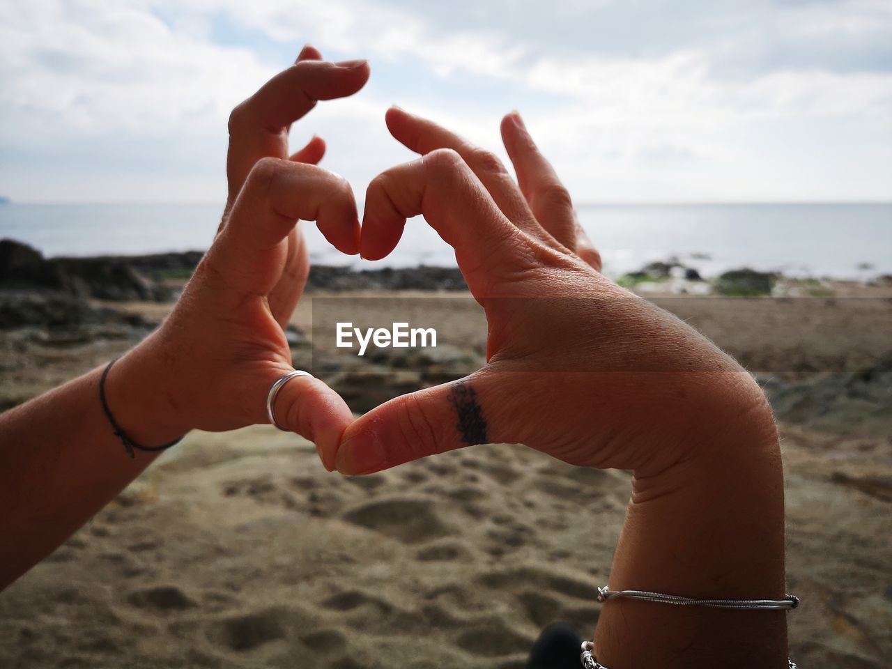 Cropped hands making heart shape at beach