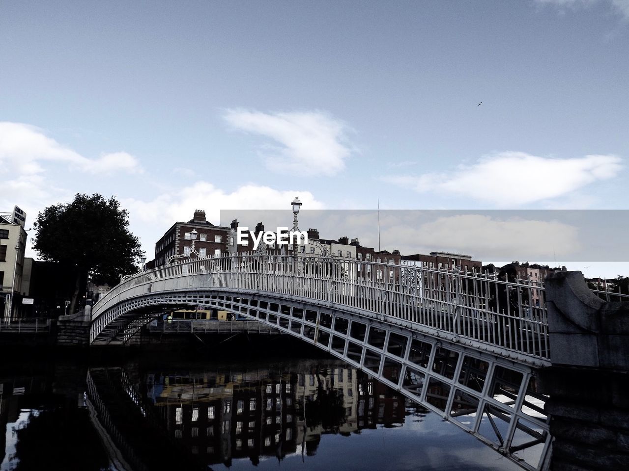 ARCH BRIDGE OVER RIVER AMIDST BUILDINGS AGAINST SKY