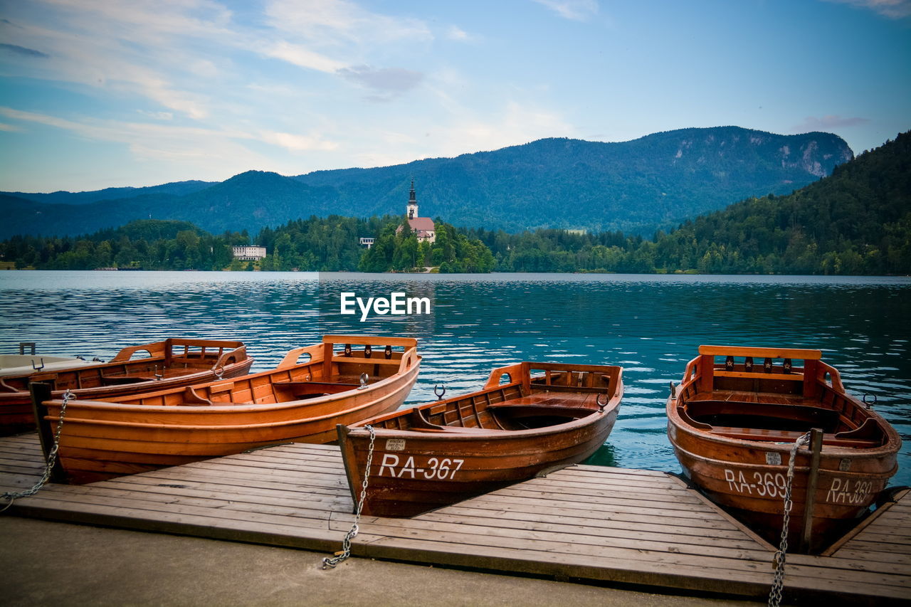 Boats moored on lake against sky