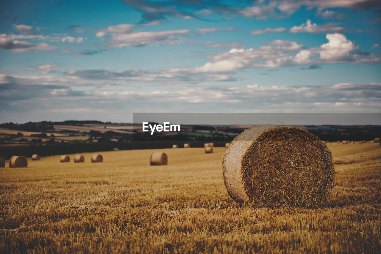 Hay bales on field against sky