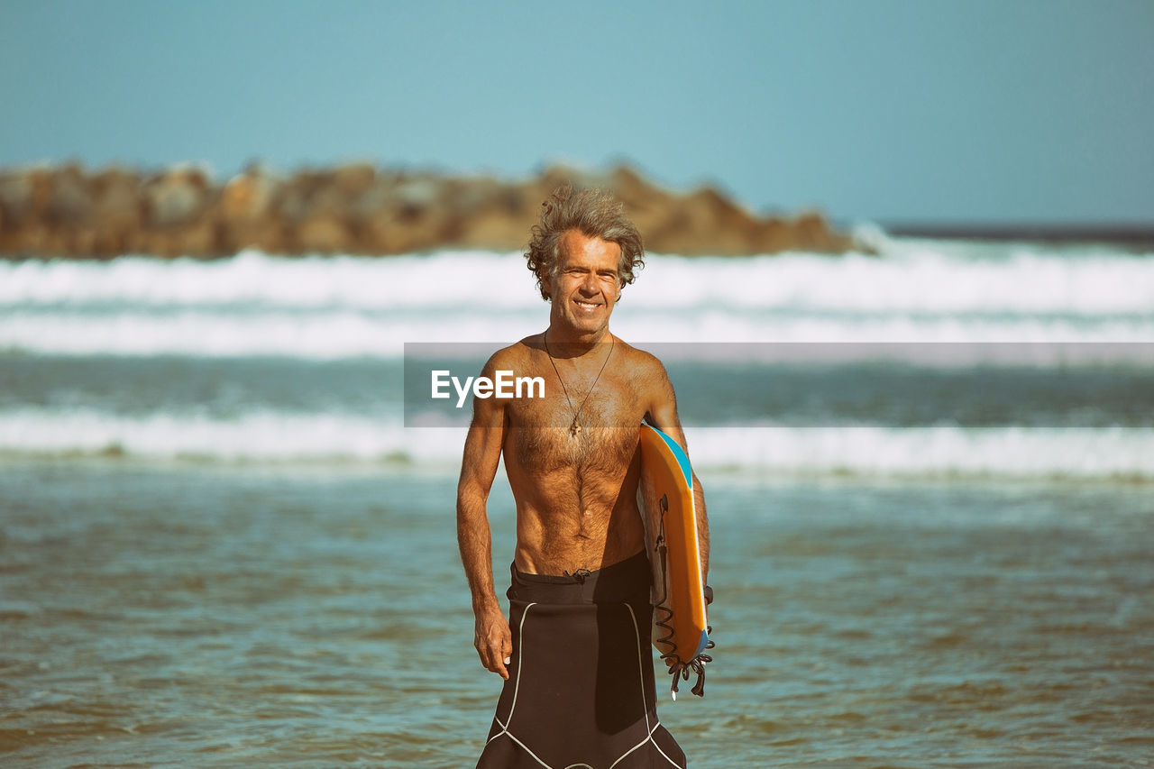 Portrait of shirtless man standing on beach