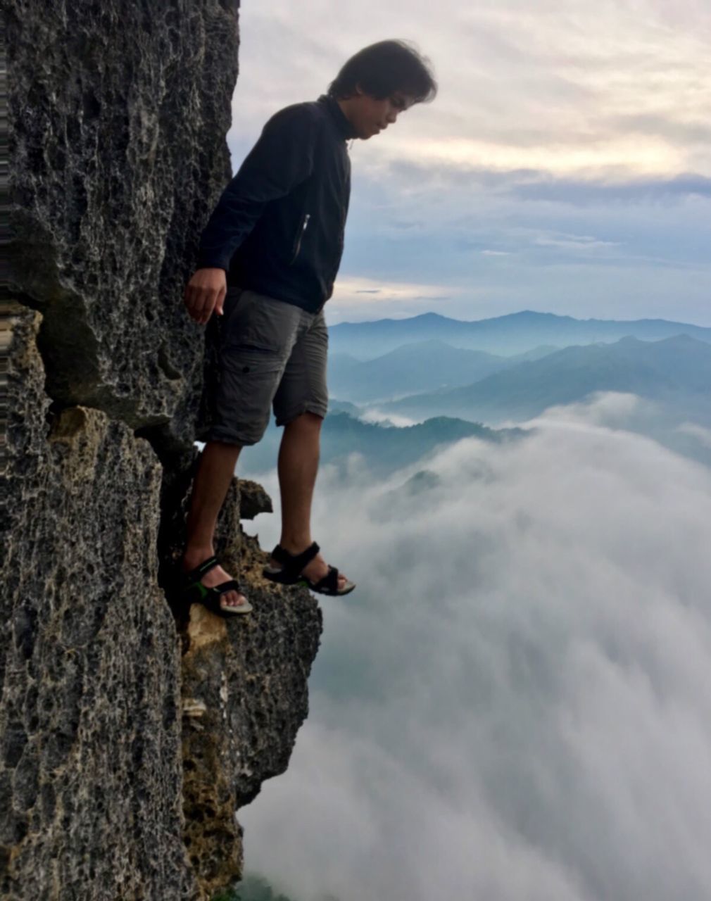 Full length of man standing on cliff against cloudy sky