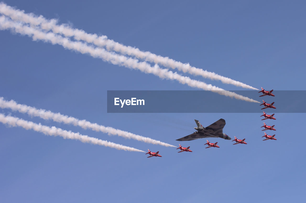 LOW ANGLE VIEW OF AIRSHOW AGAINST VAPOR TRAIL