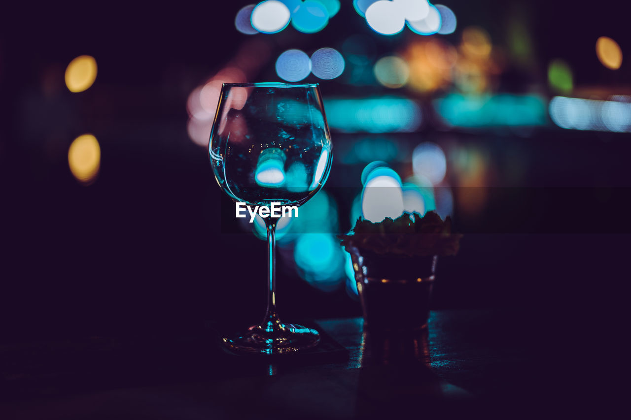 Close-up of empty wineglass on table against illuminated lights