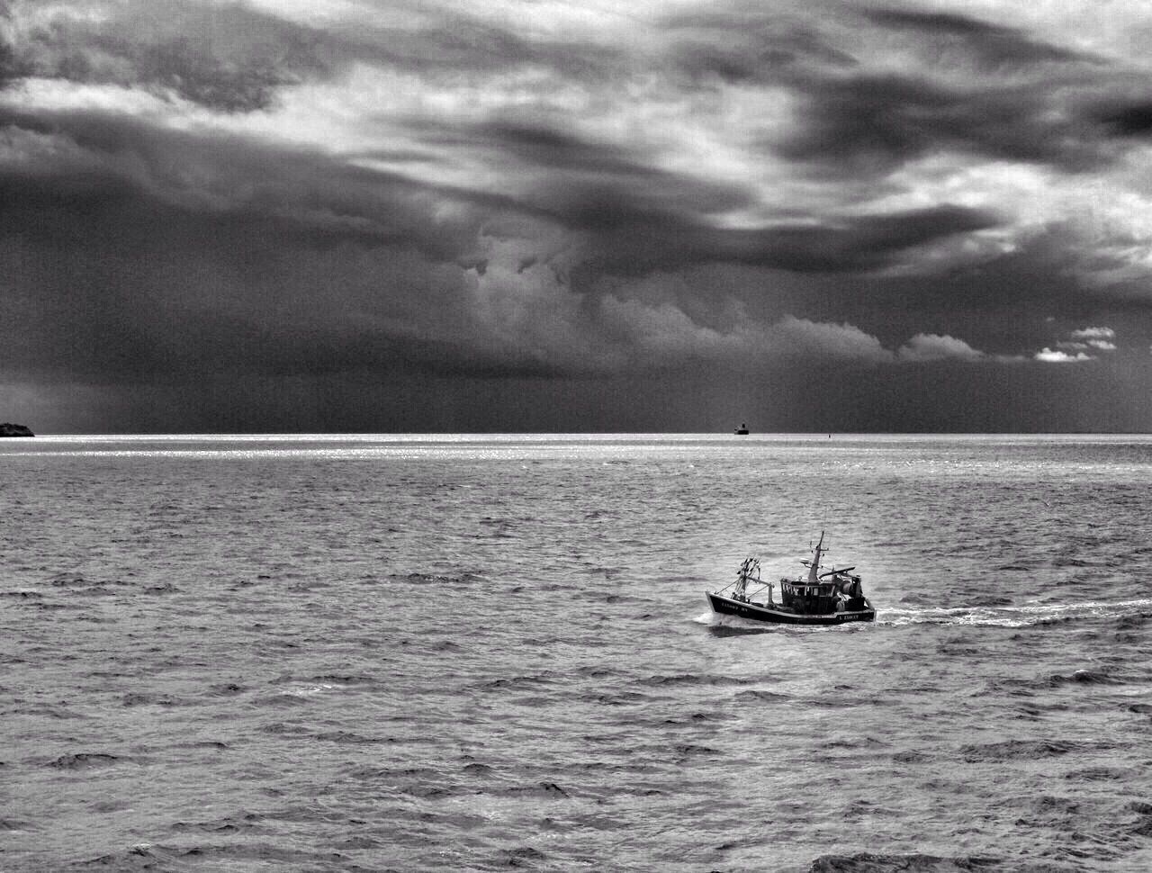 Lone boat in calm sea against clouds