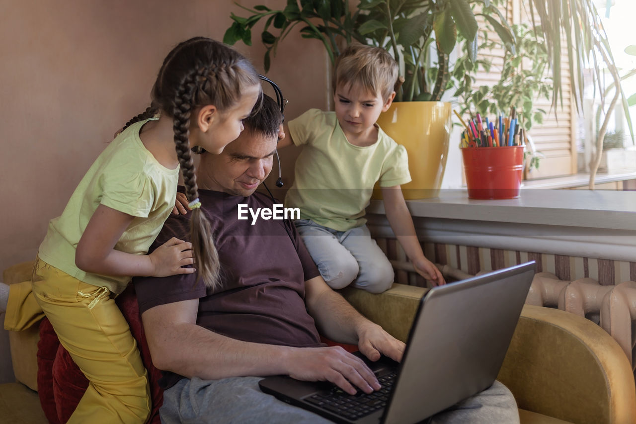 REAR VIEW OF WOMEN SITTING ON LAPTOP