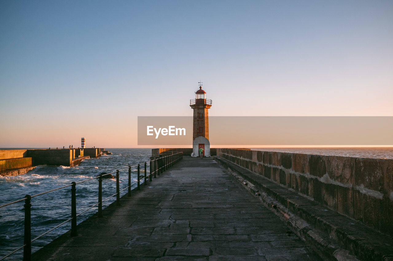 Scenic view of lighthouse on pier at sunset