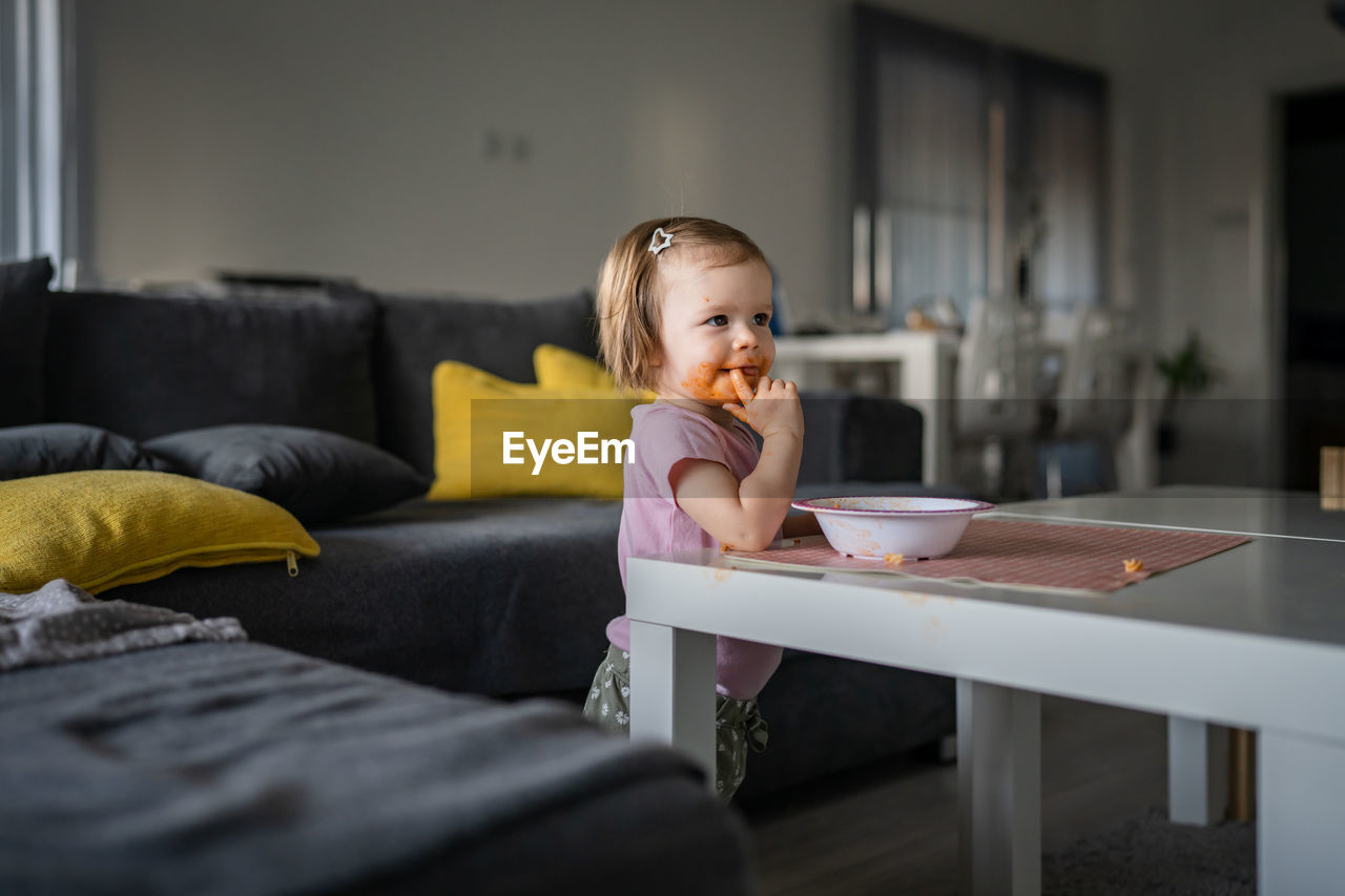 portrait of young woman using mobile phone while sitting on sofa at home