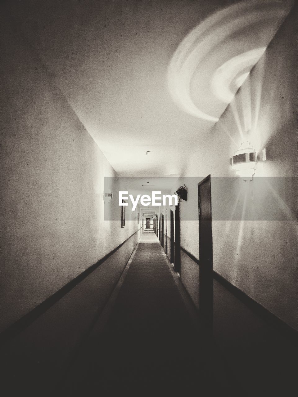 EMPTY CORRIDOR ALONG ILLUMINATED BUILDING