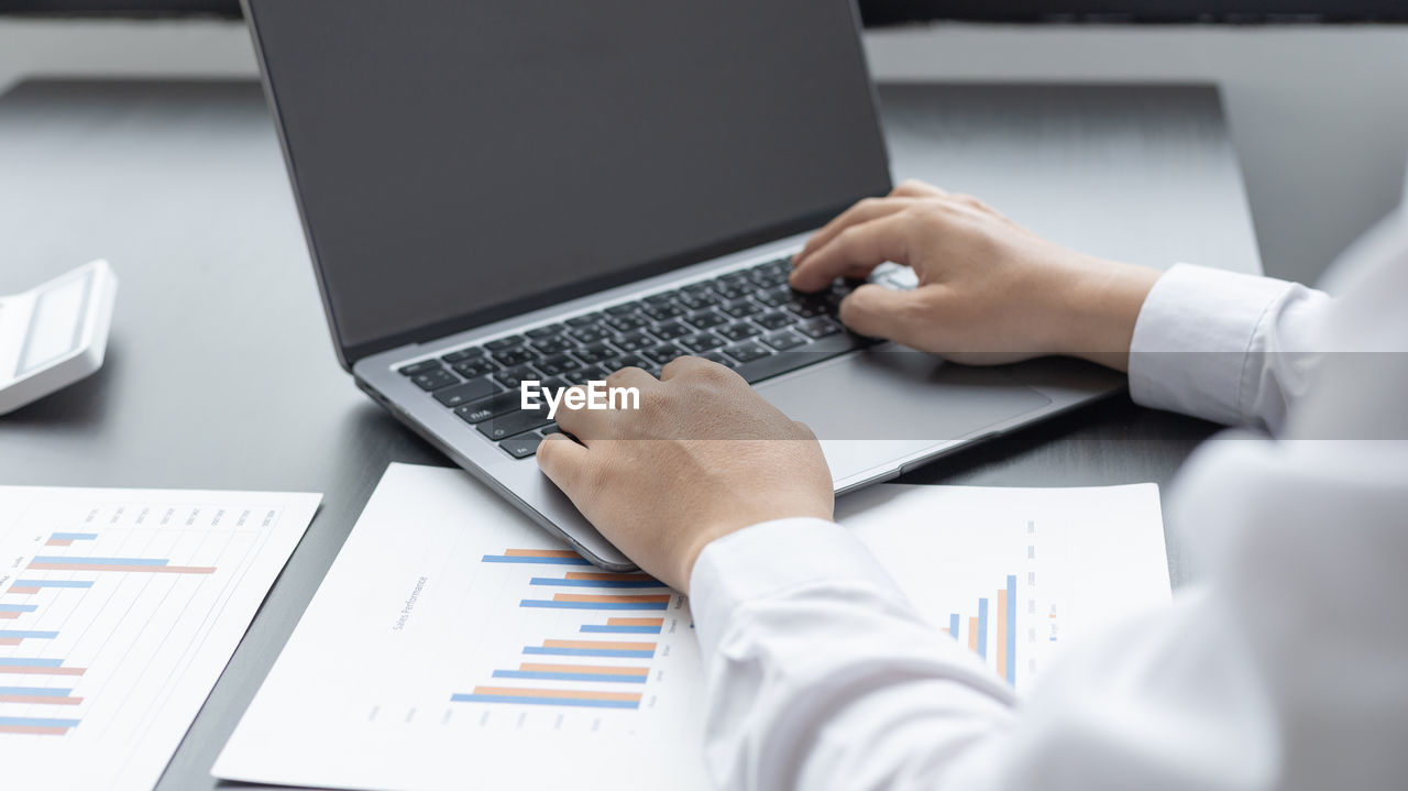 Low section of man using laptop on table