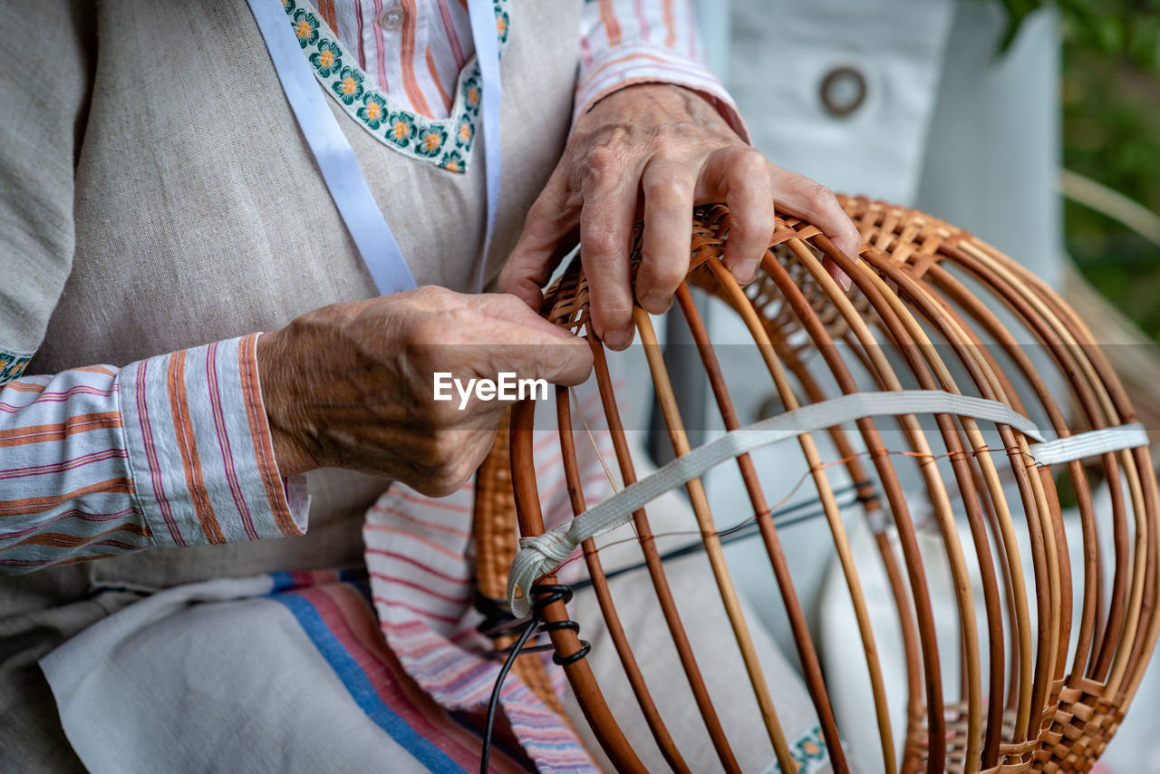Midsection of woman making basket