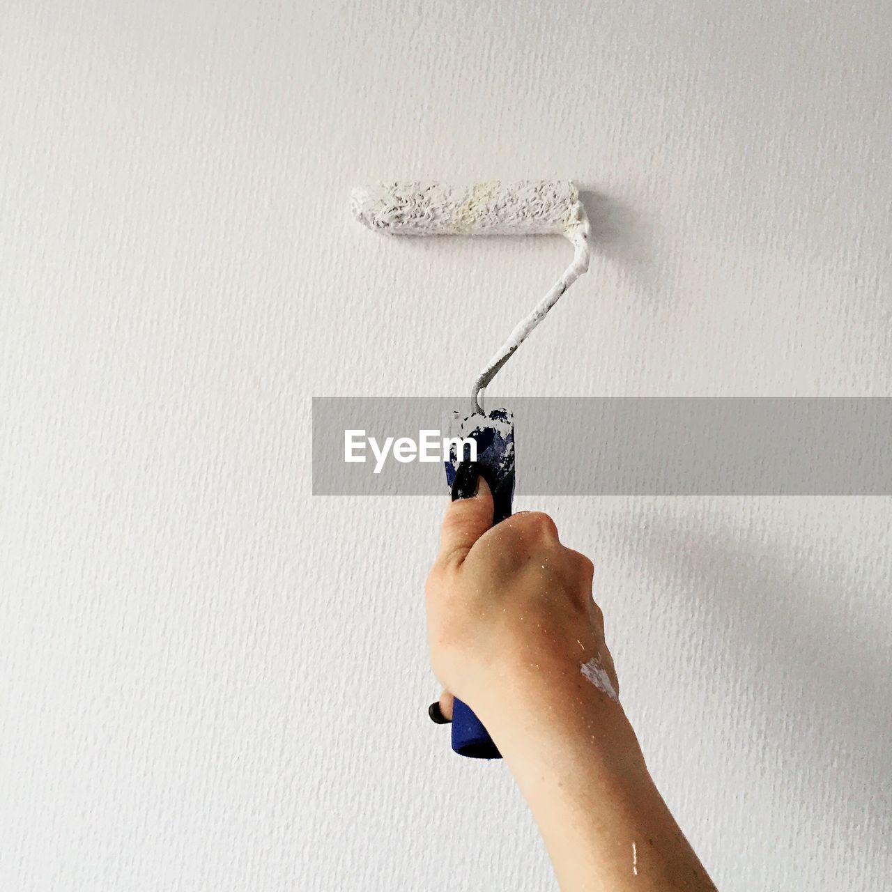 Cropped hand of woman painting wall at home