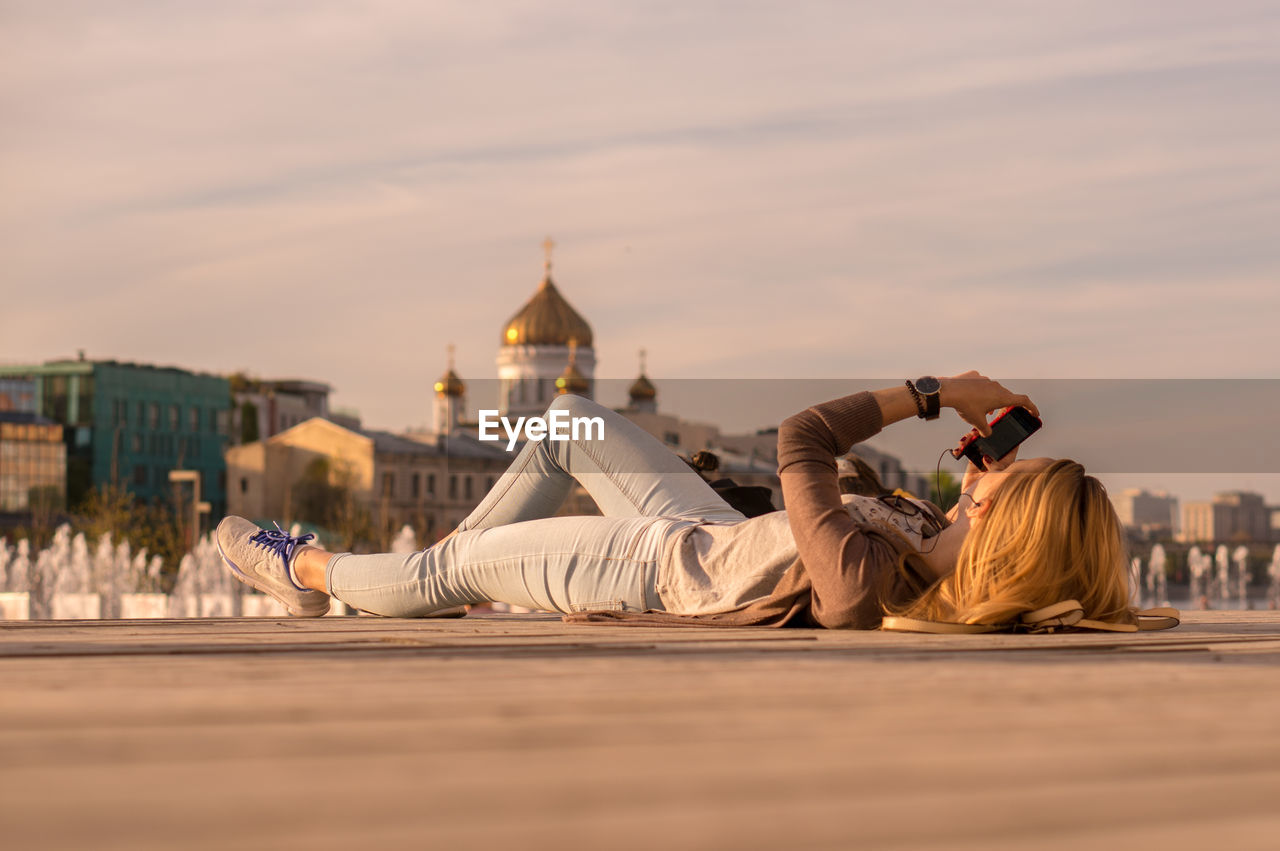 Surface level view of woman using mobile phone while lying on walkway against temple of christ the savior