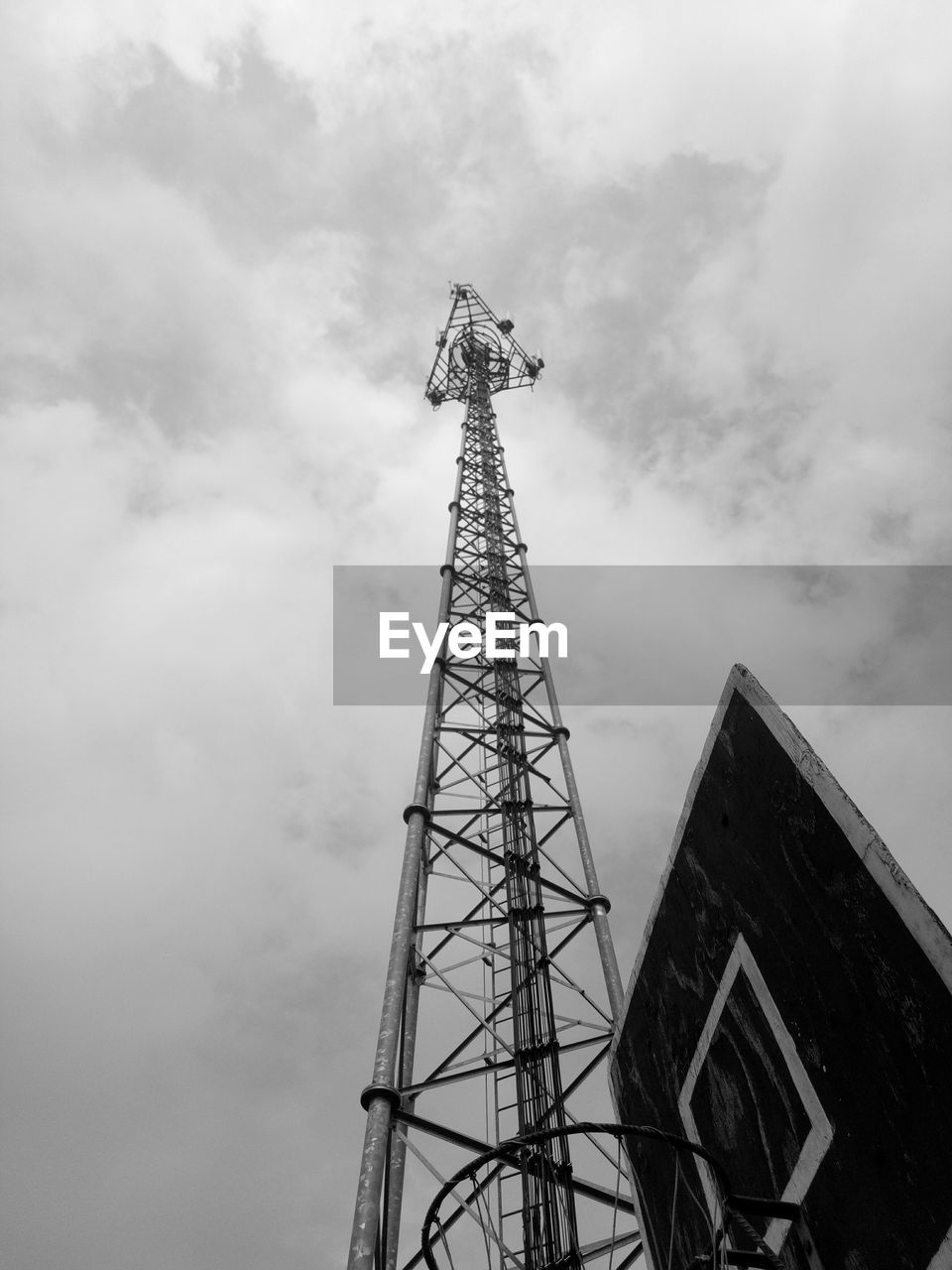 LOW ANGLE VIEW OF COMMUNICATIONS TOWER BY BUILDING AGAINST SKY