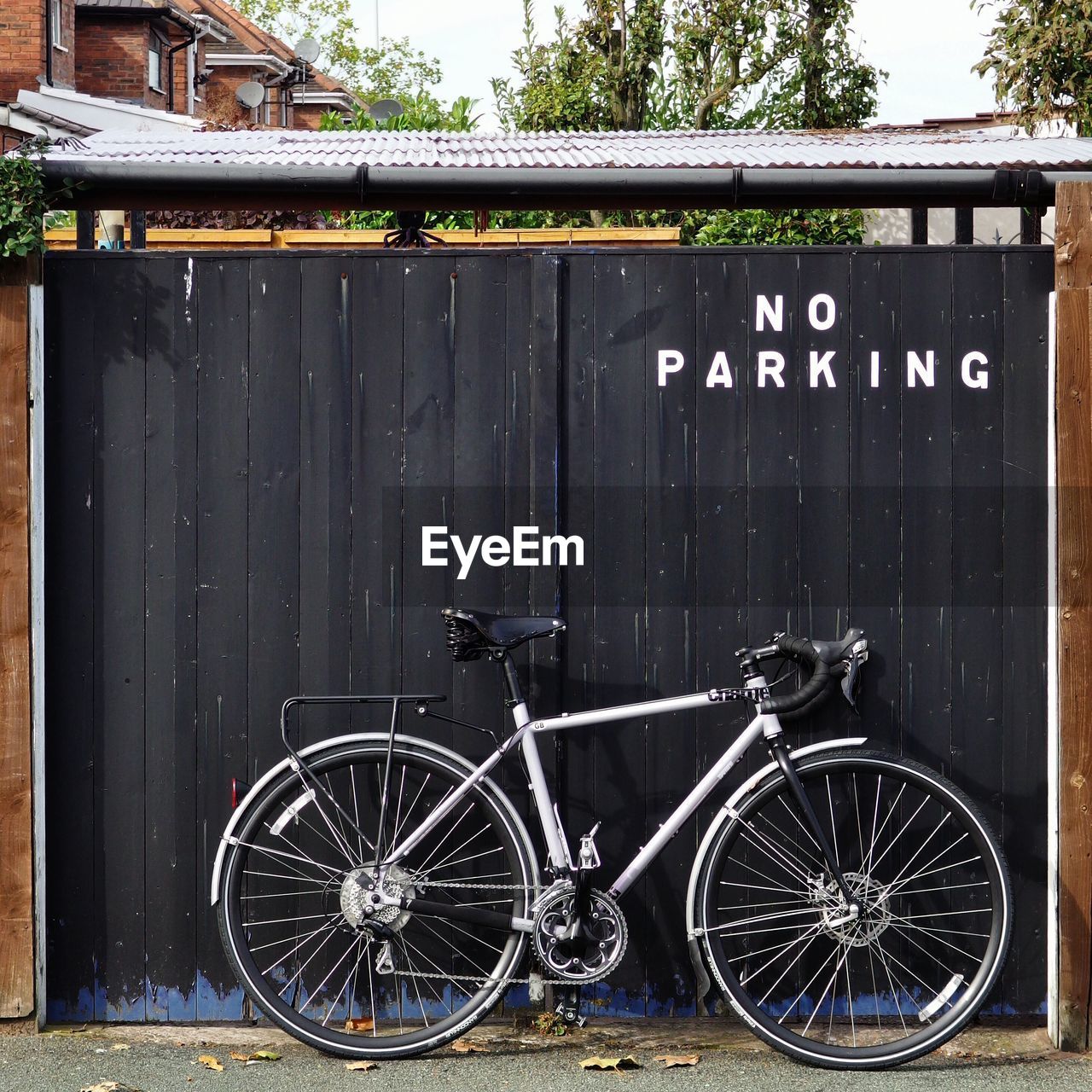 Bicycle parked against gate with no parking sign