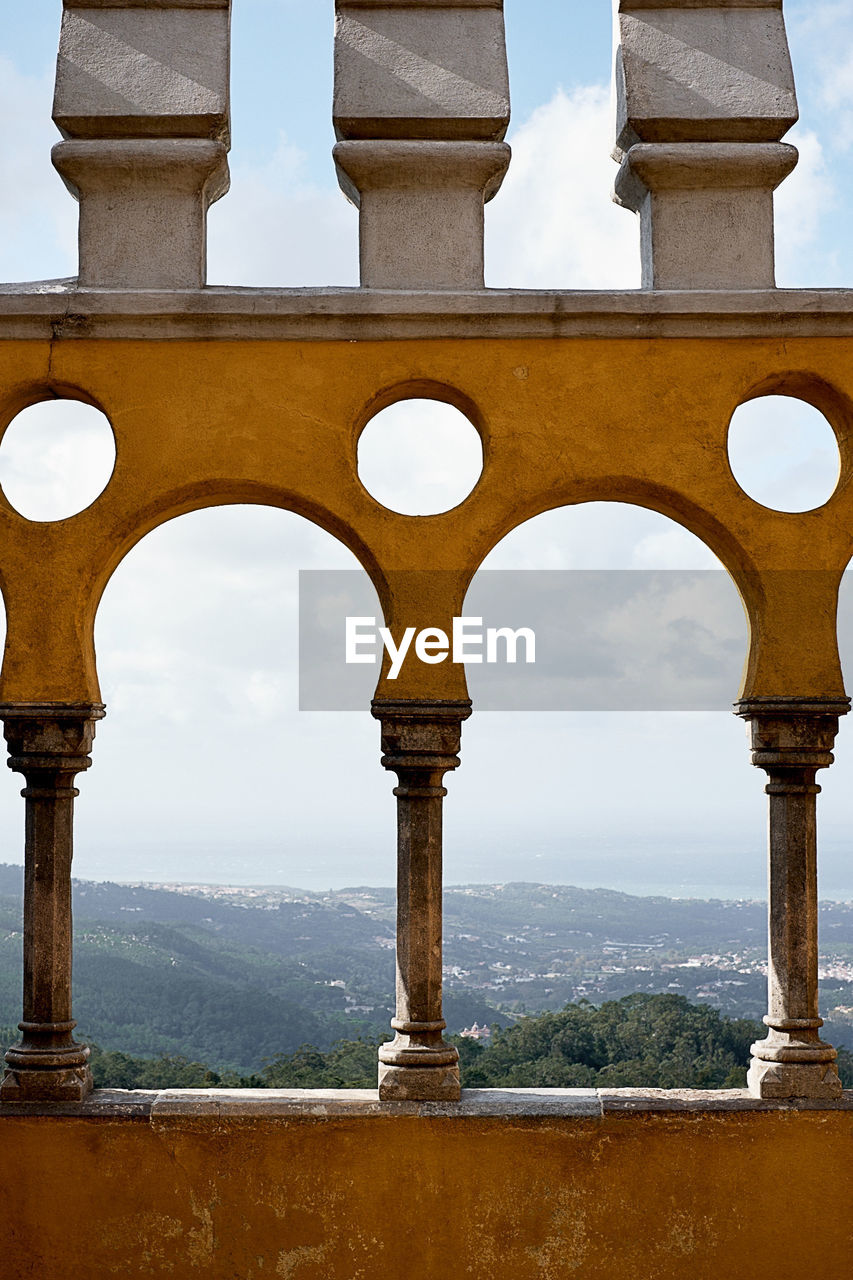 VIEW OF HISTORIC BUILDING AGAINST SKY SEEN THROUGH COLUMNS