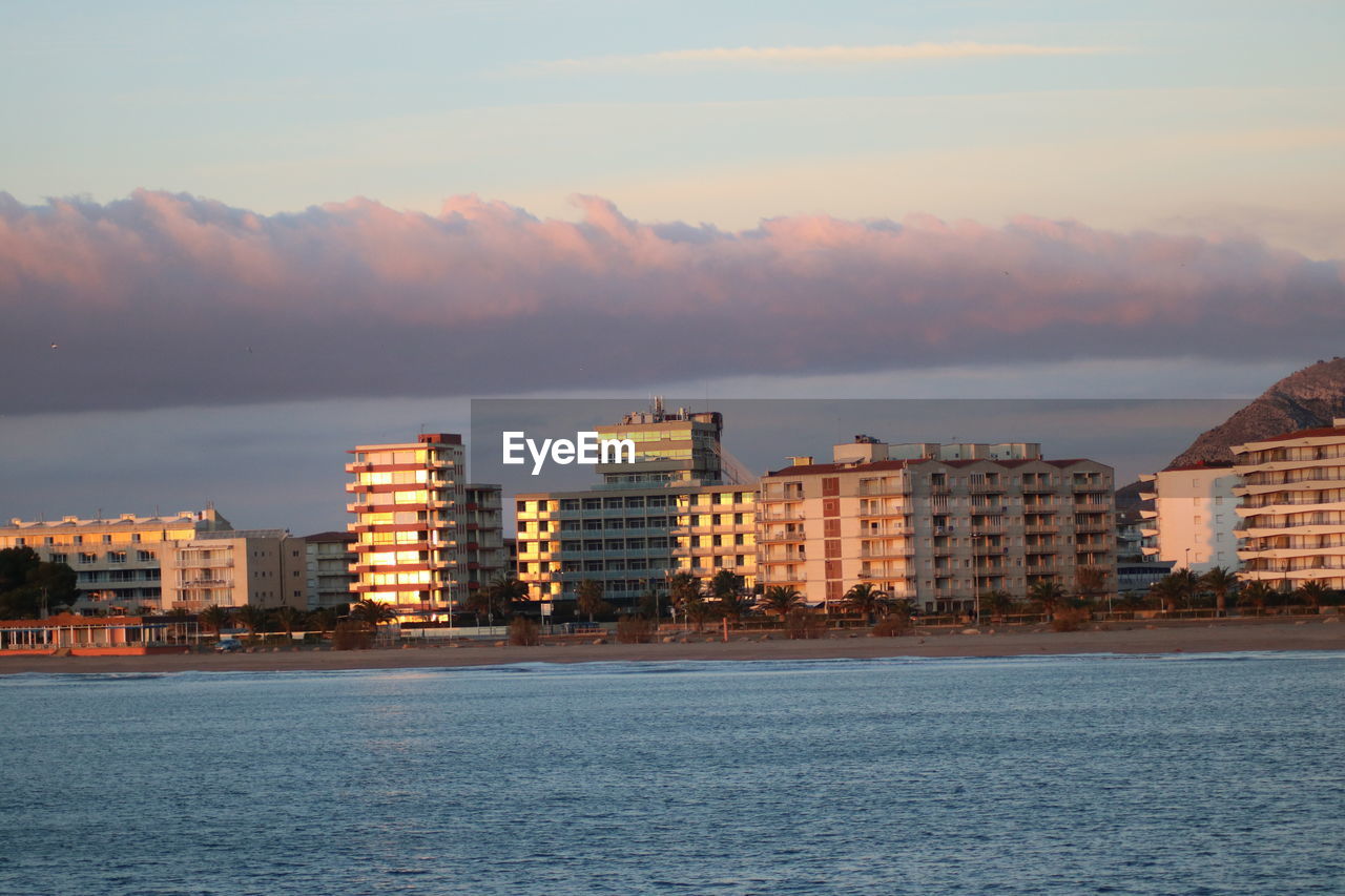 SEA BY BUILDINGS AGAINST SKY