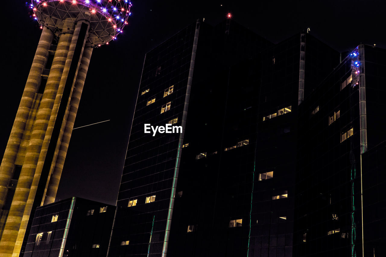 LOW ANGLE VIEW OF ILLUMINATED BUILDINGS AT NIGHT