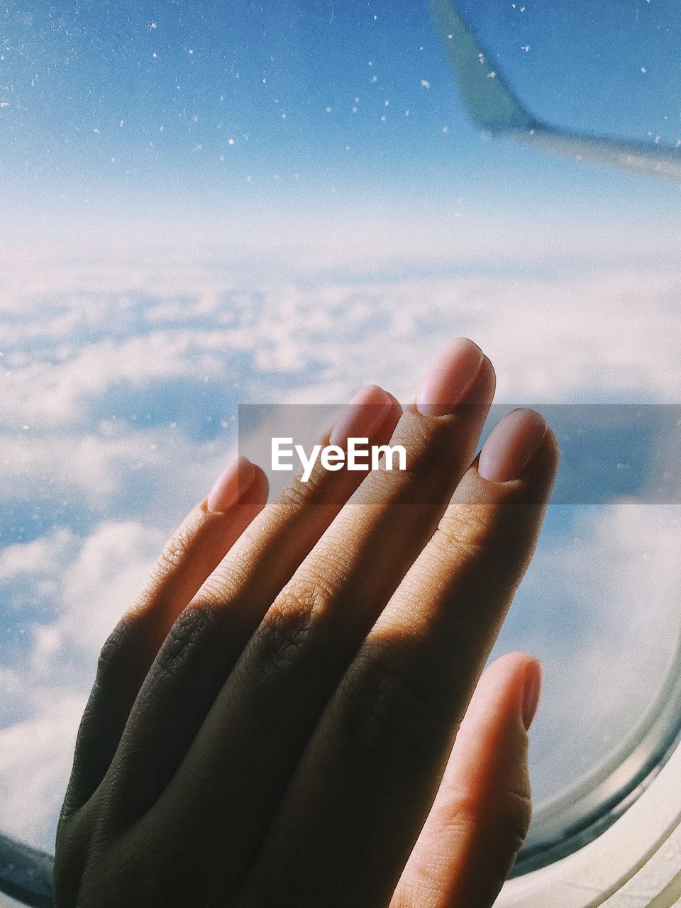 Close-up of woman hand on airplane window